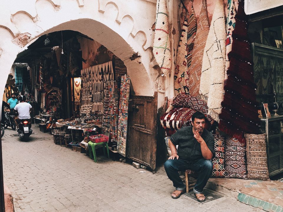 calle del zoco en marruecos y hombre mirando a la derecha sentado 